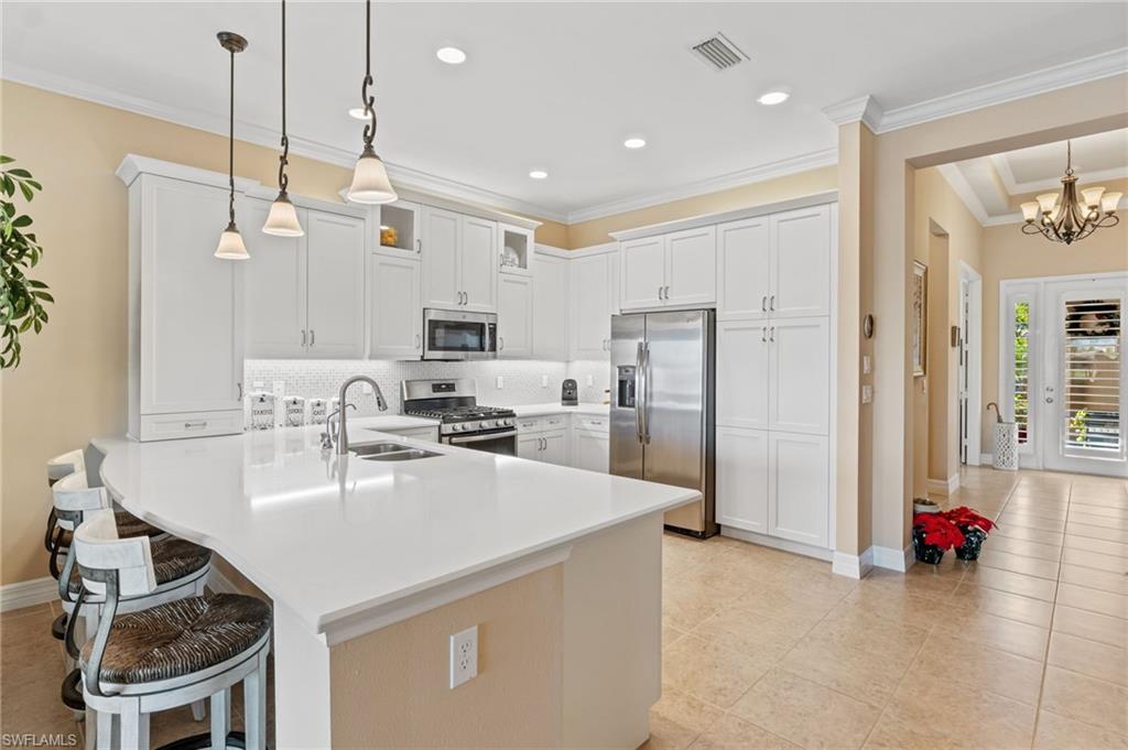 4339 Aurora Street Naples, FL 34119 - Photo 6 of 47 a kitchen with sink a refrigerator and chairs