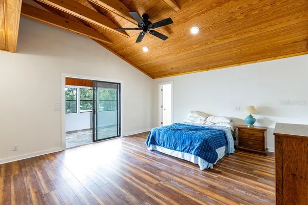 a spacious bedroom with a bed and wooden floor