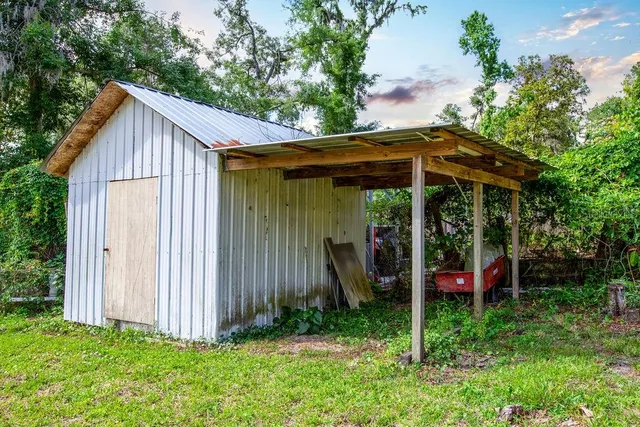 a view of barn with a small yard and large trees