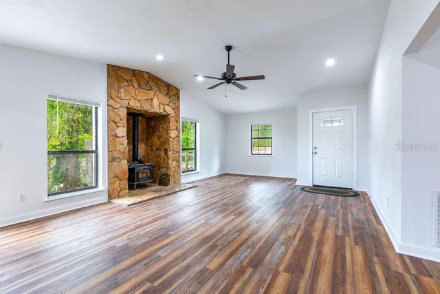 a view of an empty room with a window and wooden floor