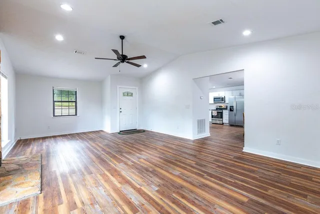 a view of an empty room and a window and wooden floor
