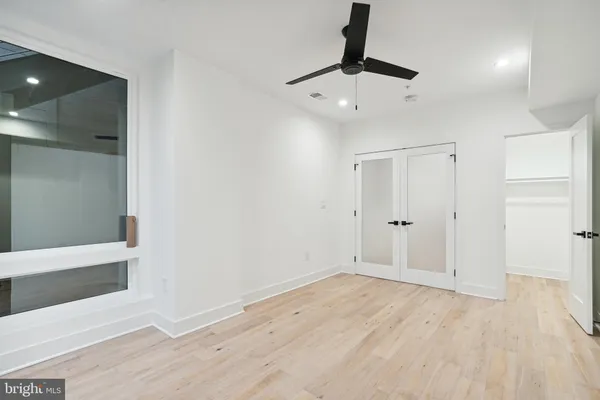 an empty room with wooden floor a ceiling fan and window