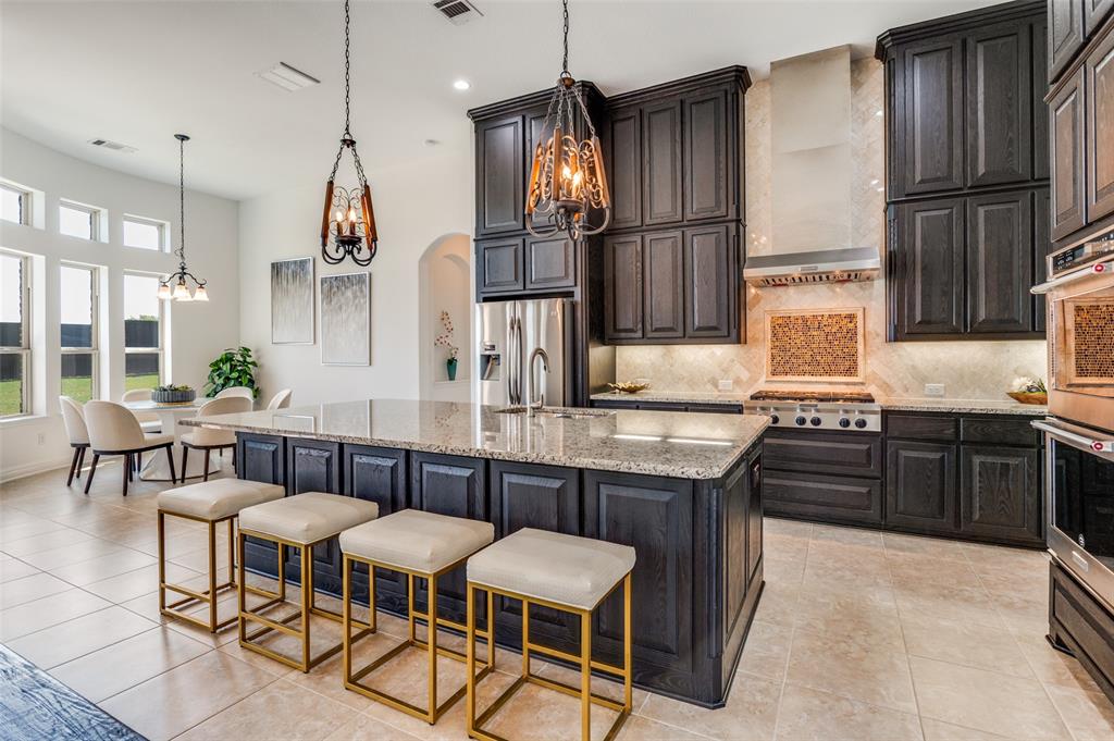 6809 Strauss Colleyville, TX 76034 - Photo 11 of 39 a kitchen with stainless steel appliances granite countertop a sink a stove a refrigerator and chairs