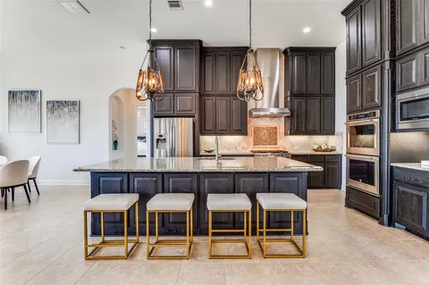 a kitchen with stainless steel appliances kitchen island granite countertop a table chairs sink and cabinets