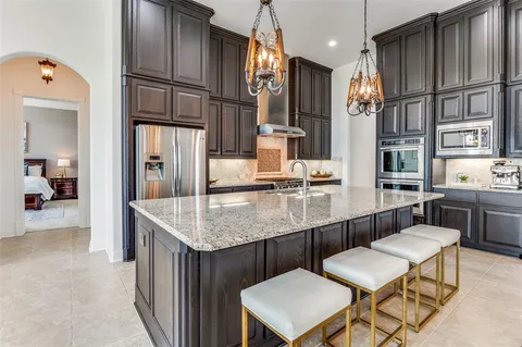 a kitchen with stainless steel appliances granite countertop a sink refrigerator and cabinets