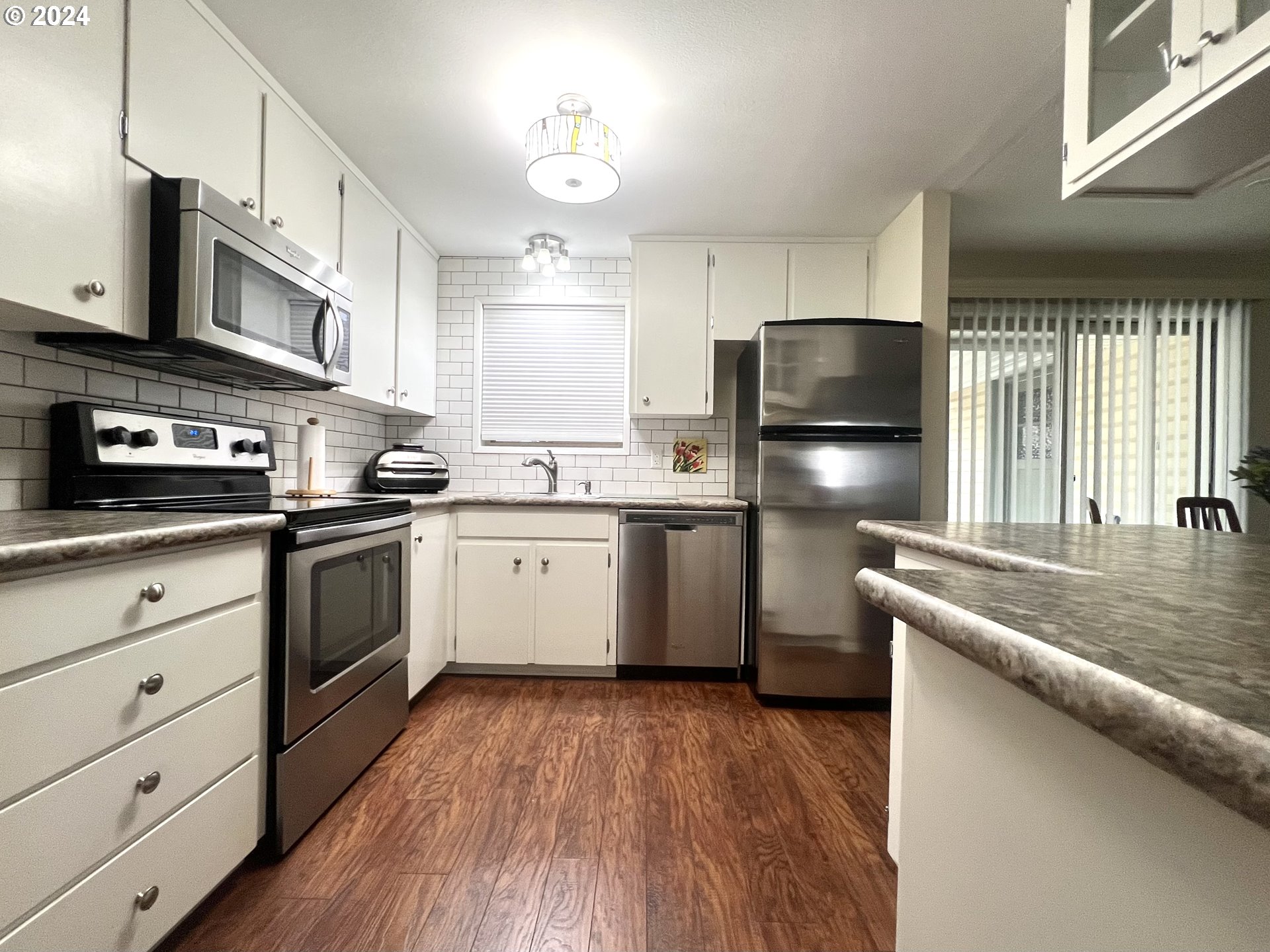 1644 Astor Way Woodburn, OR 97071 - Photo 7 of 28 a kitchen with a sink a stove a refrigerator and white cabinets