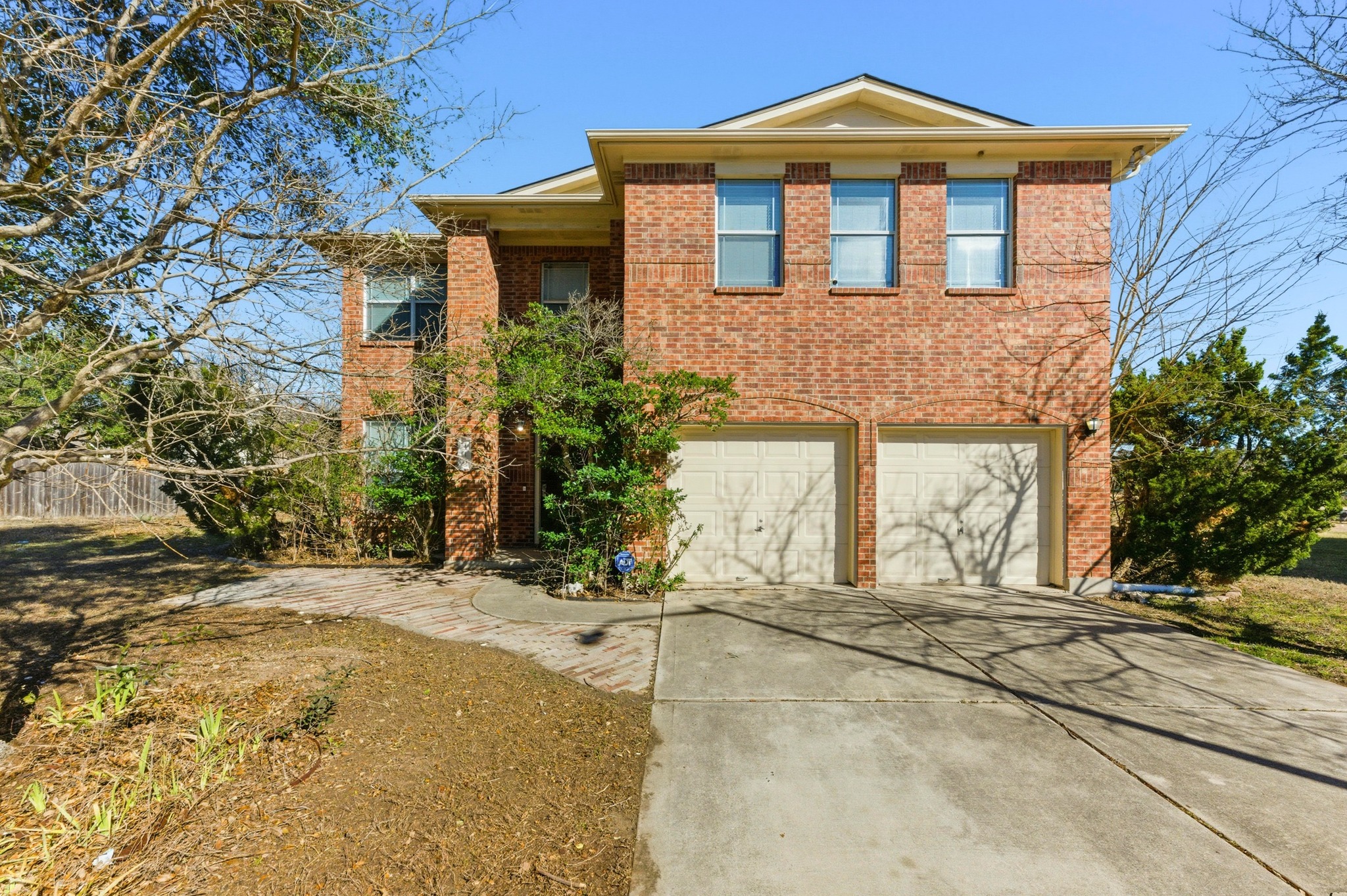 View of front facade featuring a garage, driveway, and brick siding