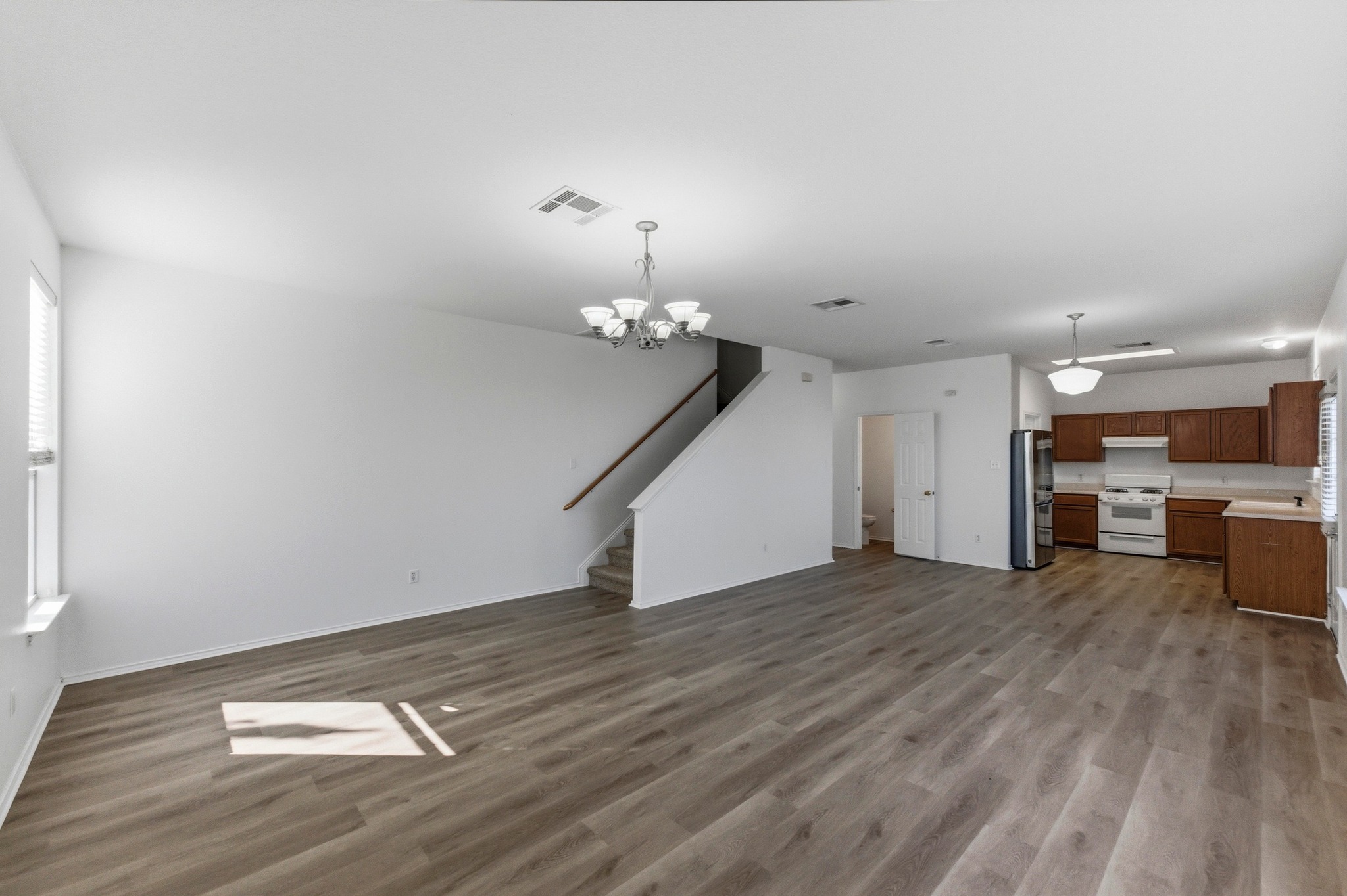 113 Spring Branch Cove Kyle, TX 78640 - Photo 8 of 33 Unfurnished living room with suspended lighting and dark wood-style flooring