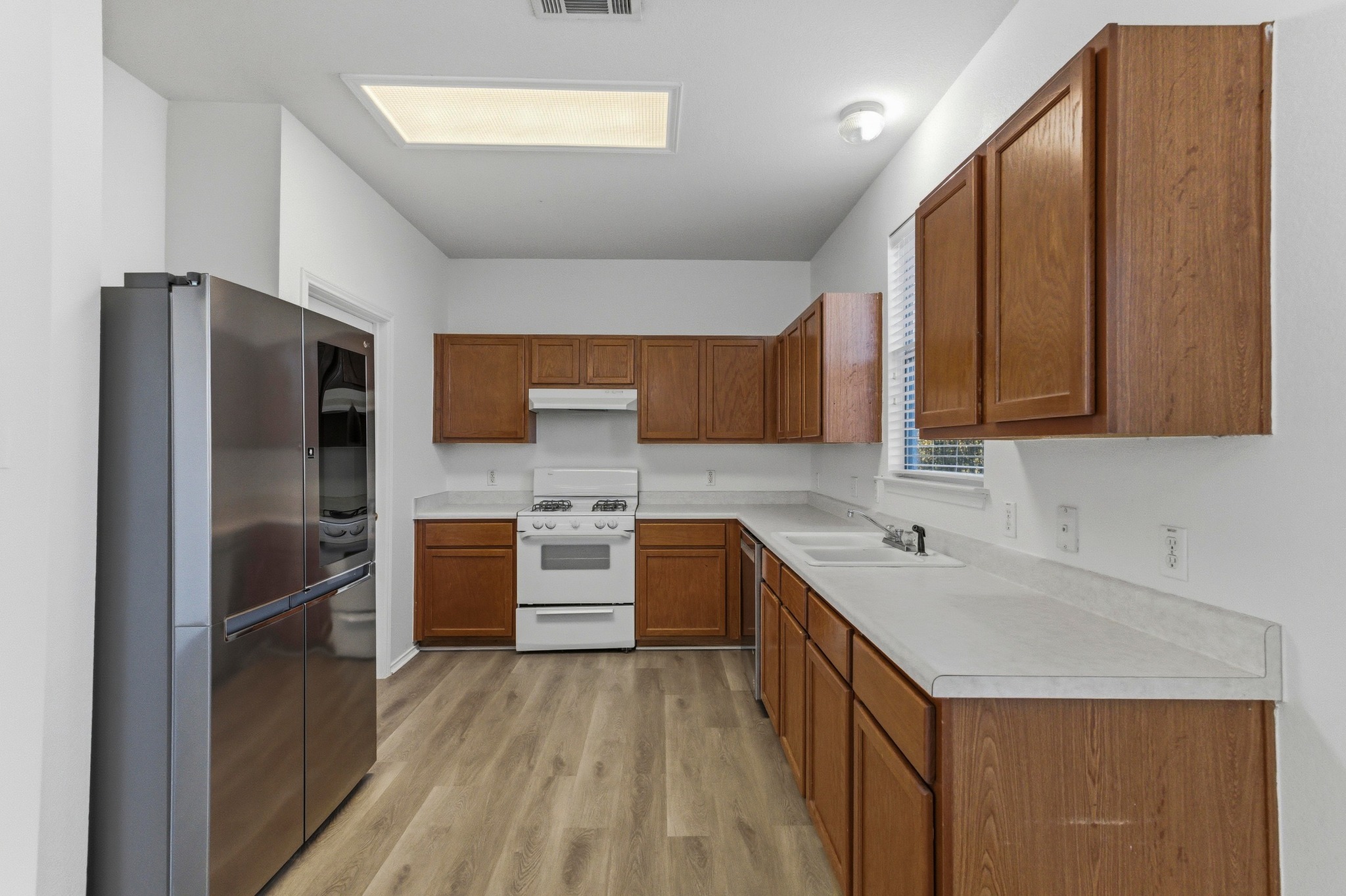 113 Spring Branch Cove Kyle, TX 78640 - Photo 10 of 33 Kitchen with wood finish cabinets, stainless steel appliances, light countertops, and light wood finished floors