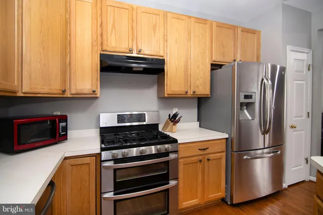 a kitchen with stainless steel appliances granite countertop a refrigerator a stove a sink and dishwasher with wooden floor