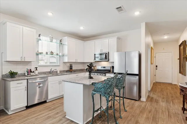 a kitchen with refrigerator a stove a sink and white cabinets with wooden floor