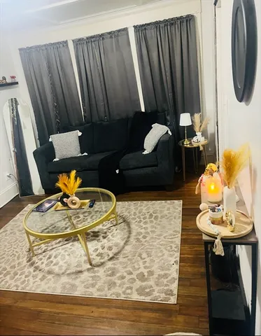 a living room with table chairs and a wooden floor