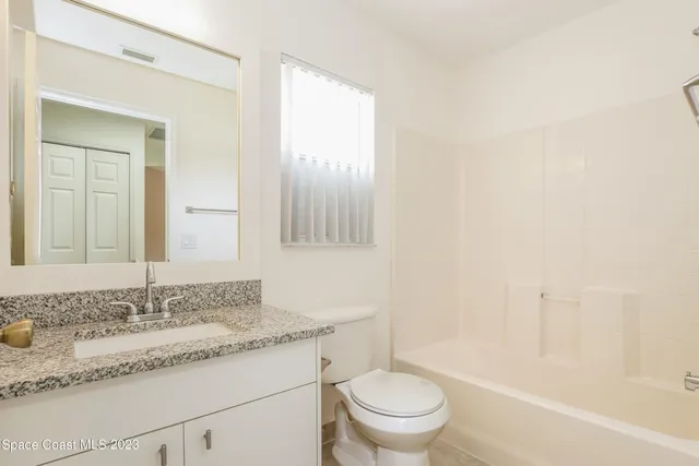 a bathroom with a granite countertop sink mirror vanity and toilet