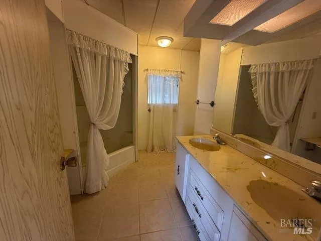 a bathroom with a granite countertop sink a mirror and a bathtub