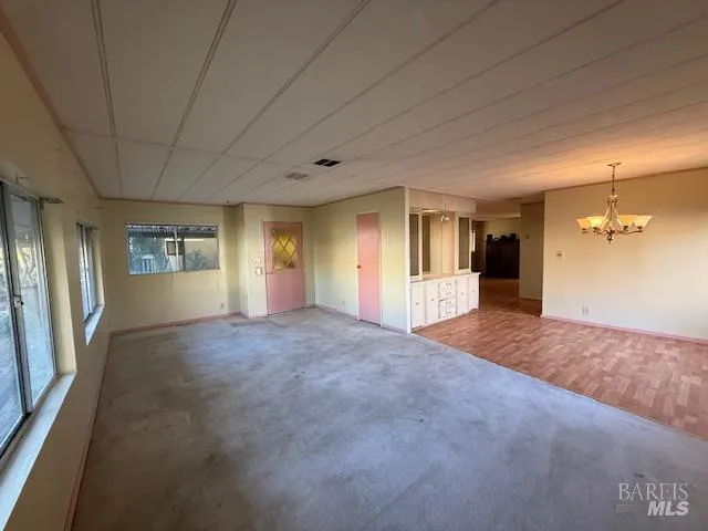 a view of a hallway with wooden floor and a kitchen