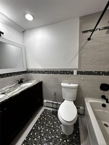 a bathroom with a granite countertop toilet sink and mirror