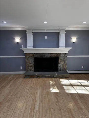a view of empty room with wooden floor and a fireplace