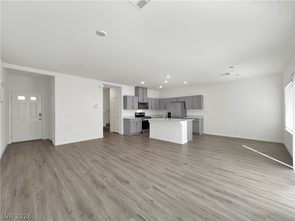 9984 Indigo Cliffs Street Las Vegas, NV 89141 - Photo 8 of 31 Unfurnished living room with visible vents, baseboards, recessed lighting, light wood-style flooring, and a sink