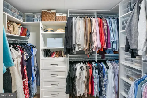 a view of walk in closet with clothes and shoes