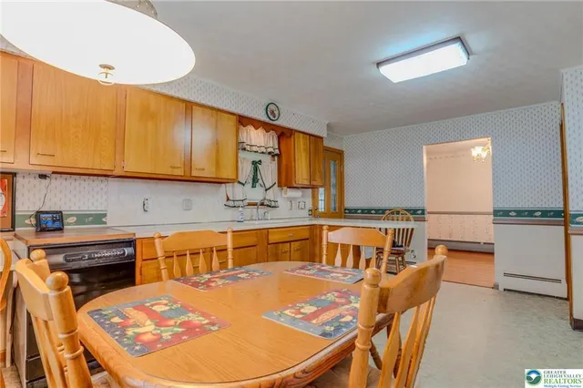 a kitchen with stainless steel appliances granite countertop a sink a stove a dining table and chairs