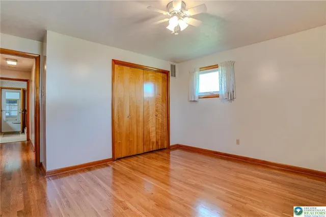 a view of empty room with wooden floor and fan