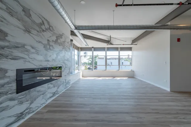a view of an empty room with a window and fireplace