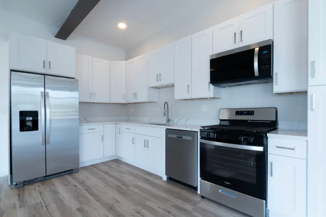 a kitchen with stainless steel appliances a stove a microwave a sink and cabinets
