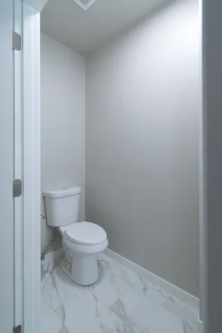 a white toilet sitting next to a white wall
