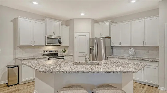 a kitchen with kitchen island granite countertop a sink and refrigerator