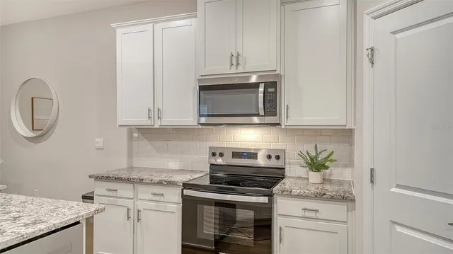 a kitchen with granite countertop white cabinets and a stove
