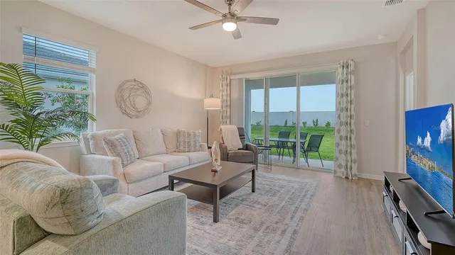 a living room with furniture a flat screen tv and a large window