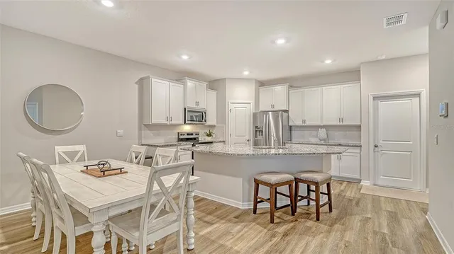 a kitchen with kitchen island granite countertop a wooden floor and white cabinets