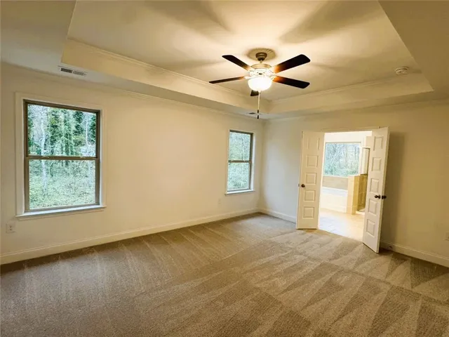 a view of an empty room with window and chandelier fan