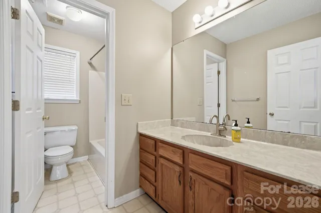 a bathroom with a granite countertop sink a toilet and a mirror