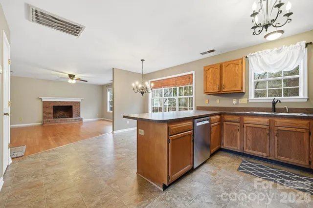 a kitchen with stainless steel appliances granite countertop a sink dishwasher a stove and a refrigerator with wooden floor