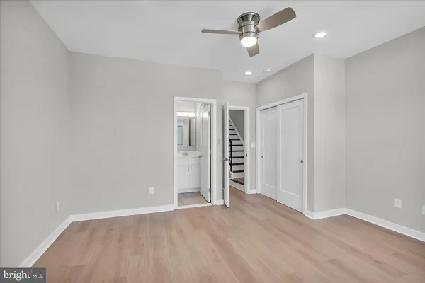 an empty room with wooden floor and ceiling fan