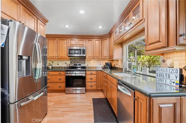 a kitchen with stainless steel appliances granite countertop a refrigerator a sink and a stove