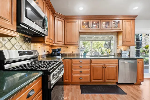 a kitchen with stainless steel appliances granite countertop a stove a sink and a microwave