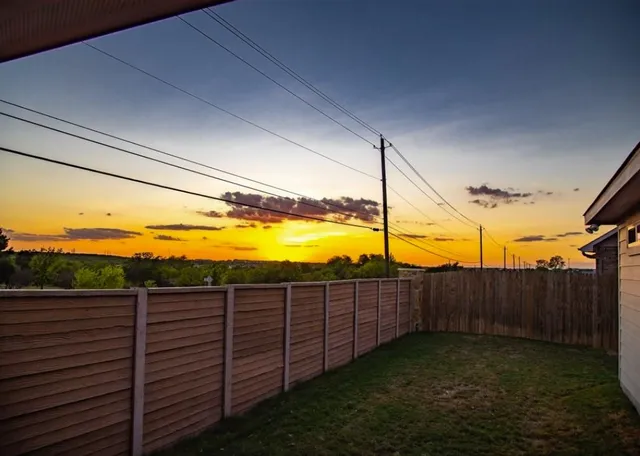 a view of a yard with wooden fence