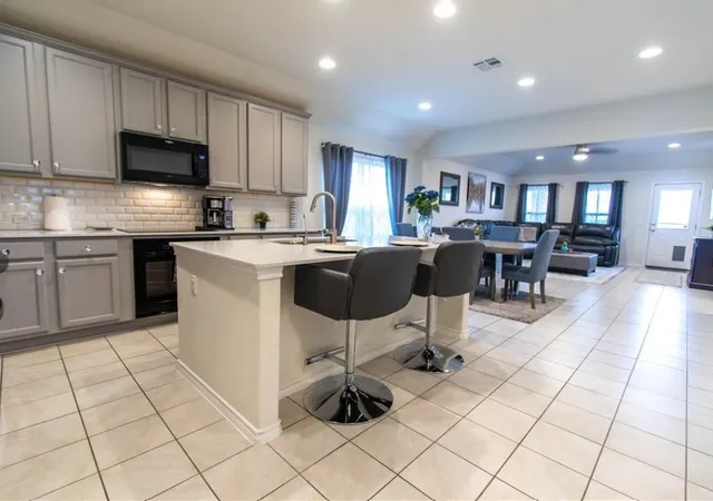 a kitchen with stainless steel appliances kitchen island granite countertop a sink a stove a dining table and chairs