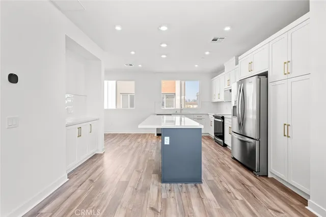 a kitchen with stainless steel appliances granite countertop a refrigerator a sink dishwasher a stove and white countertops with wooden floor