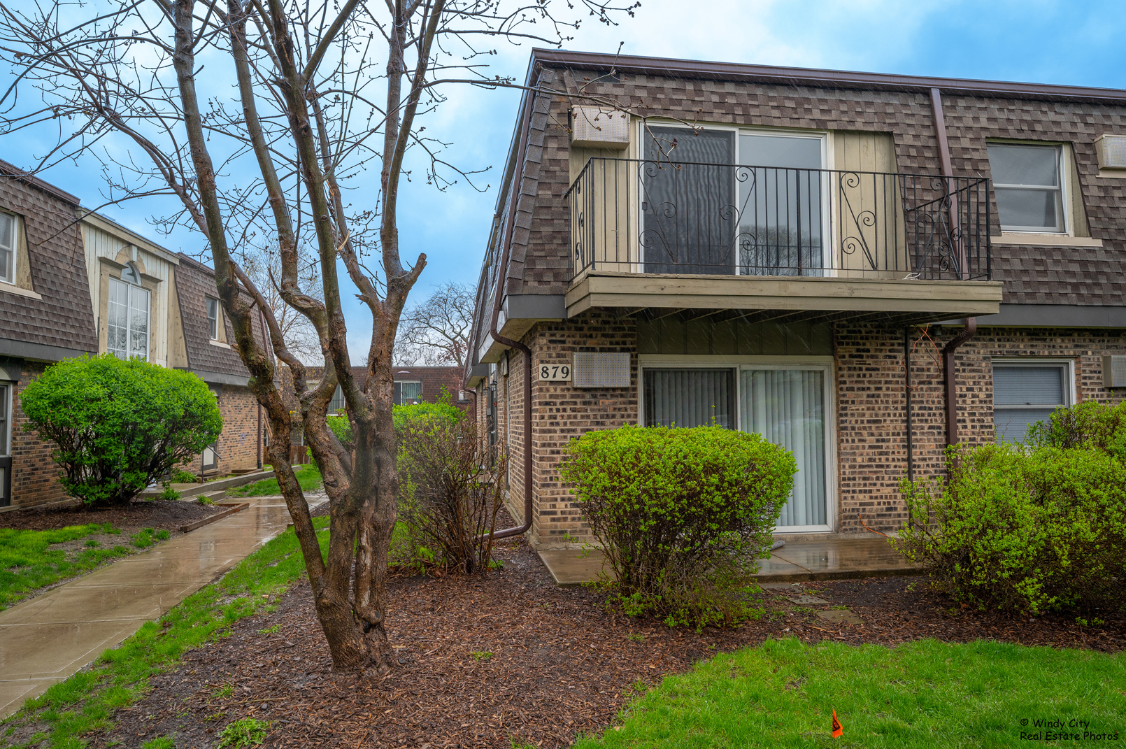 879 Trace Drive, Unit 202 Buffalo Grove, IL 60089 - Photo 3 of 15 a view of a brick house with a large windows and a large tree