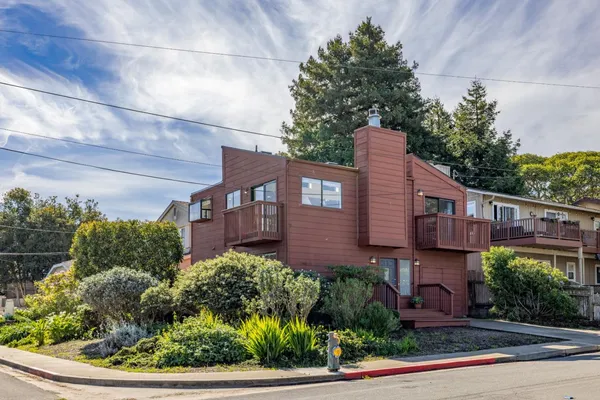 a front view of a house with a yard and potted plants