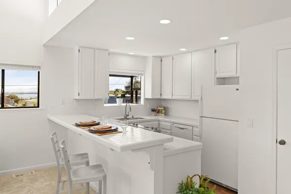 a kitchen with kitchen island white cabinets and refrigerator