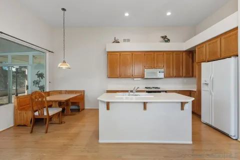 a kitchen with stainless steel appliances granite countertop a stove a refrigerator a sink a dining table and chairs with wooden floor