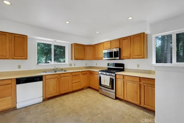 a kitchen with stainless steel appliances granite countertop wooden cabinets a sink a stove a microwave a sink and dishwasher