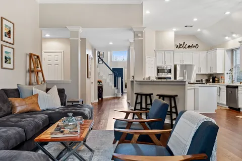 a living room with furniture kitchen view and a wooden floor