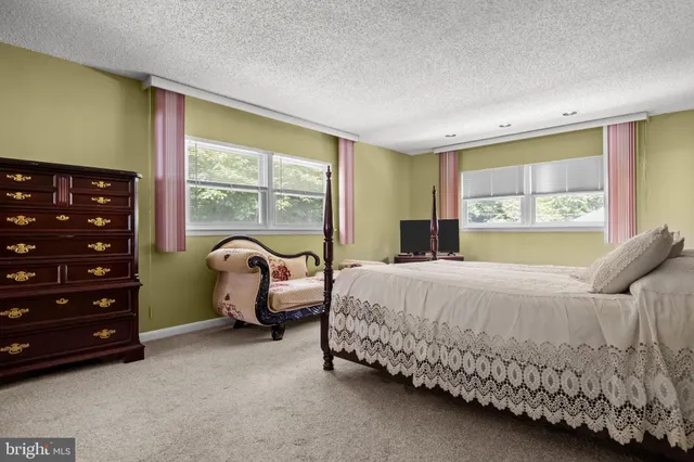 a bedroom with a bed and large windows