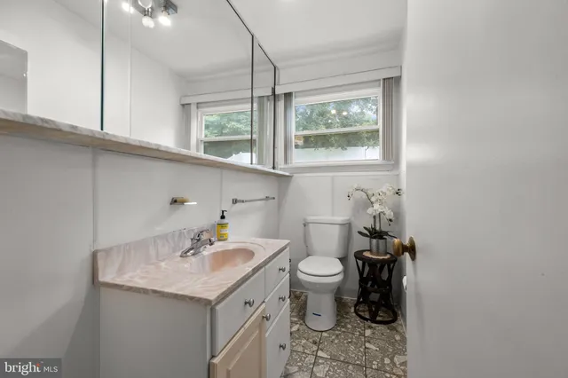 a bathroom with a granite countertop sink and a toilet