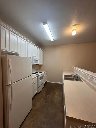 a white refrigerator freezer and a stove sitting inside of a kitchen